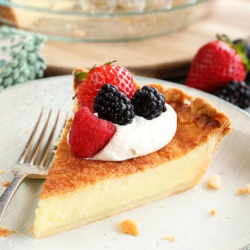 Slice of Buttermilk Pie with whipped topping and fruit on top