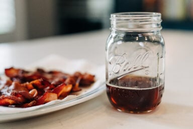 plate of bacon with jar of bacon grease.