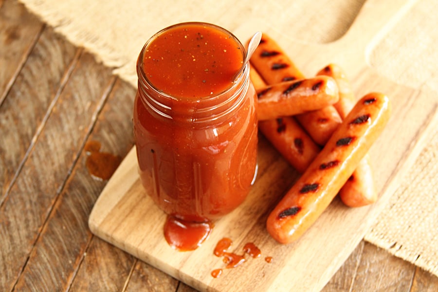 Jar of Coca Cola BBQ Sauce on wooden serving bowl with hot dogs