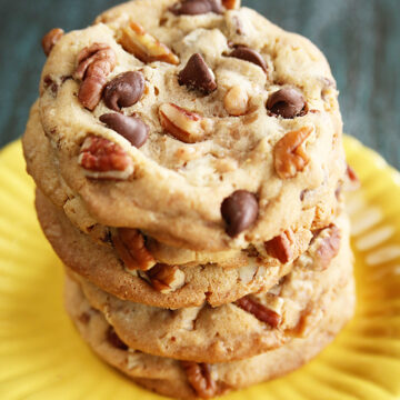 Chocolate Chip toffee Pecan Cookies stacked on yellow plate