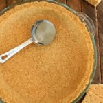 Overhead view of graham cracker crust with measuring cup.