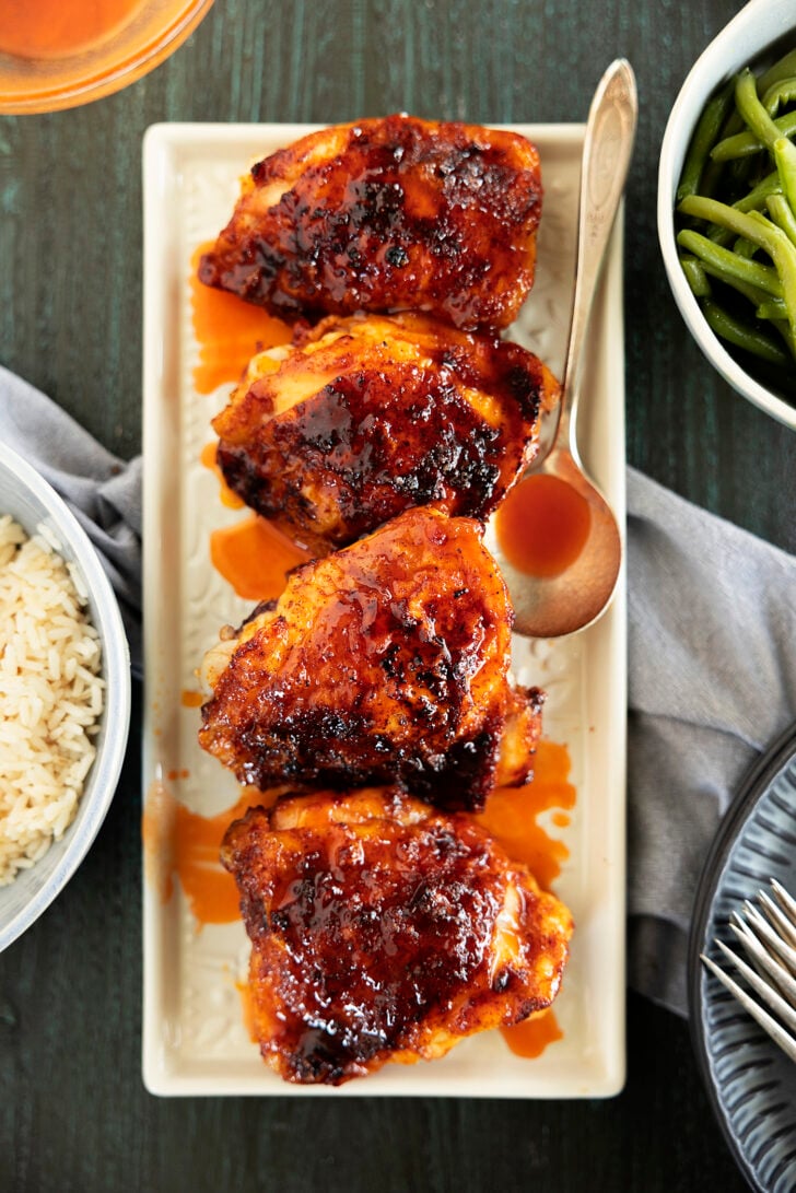 Chicken thighs on a platter with hot honey glaze.