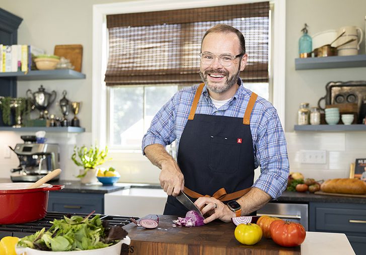 Stacey Little cutting vegetables on cutting board in kitchen